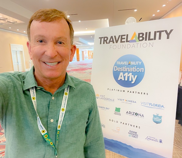 Richard Grey in front of TravelAbility Foundation Sign